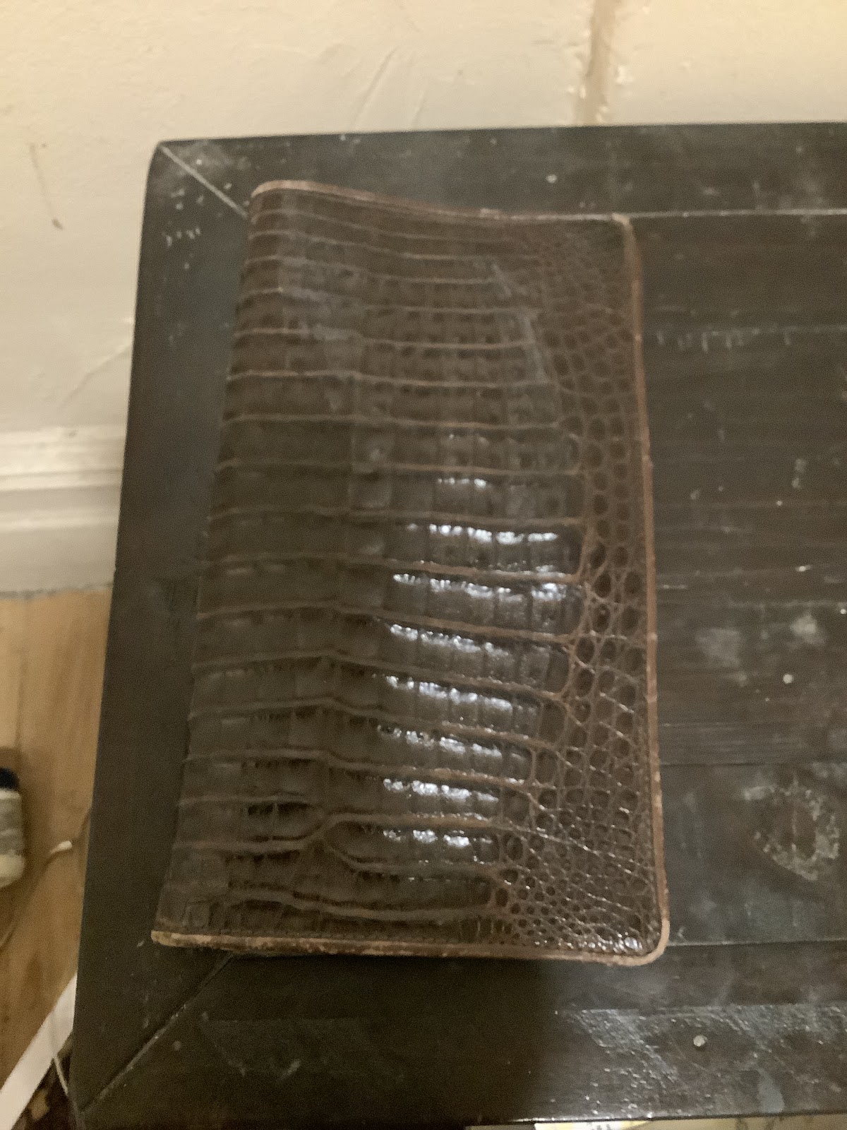 Restored brown crocodile-grain leather wallet on workbench